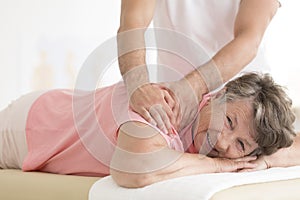 Masseur setting elderly woman shoulder