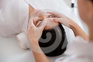 Masseuse hands massaging face of young woman