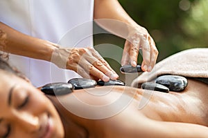 Masseuse hands placing hot stones