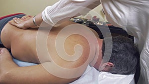 Masseuse make therapeutic massage of backbone to adult fat man. Medium shot.
