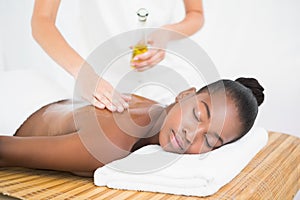 Masseuse pouring massage oil on a pretty woman back
