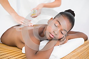 Masseuse pouring massage oil on a pretty woman back