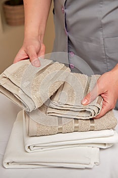 Masseuse taking clean towels from pile, preparing to receive patient