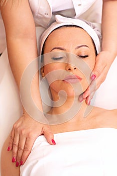 Masseuseâ€™s hands giving a neck and facial massage to a woman