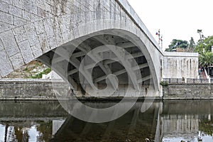 The massive arch of the stone bridge over the river.