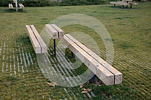 Massive bench in the park under a tree in the park urban style beam shape on metal legs in the square. grass grate made of metal a