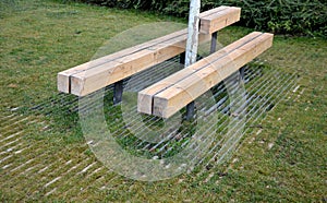 Massive bench in the park under a tree in the park urban style beam shape on metal legs in the square. grass grate made of metal a