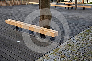 Massive bench in the park under a tree in the park urban style beam shape on metal legs in the square. grass grate made of metal a