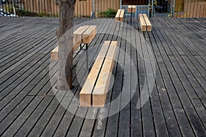 Massive bench in the park under a tree in the park urban style beam shape on metal legs in the square. grass grate made of metal a