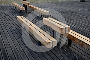 Massive bench in the park under a tree in the park urban style beam shape on metal legs in the square. grass grate made of metal a