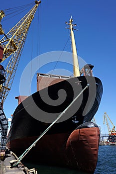 The massive bow of a large ship, with the radar dome above the surface of the water with crane, at the seaport. vertical.