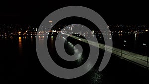 Massive bridge full of traffic at night, city with colorful lights on the background, 4k