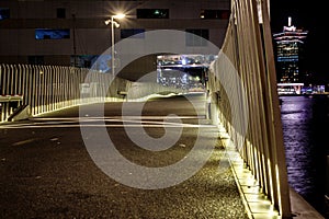 Massive bridge with lights next to the sea with city skyline in the back at night