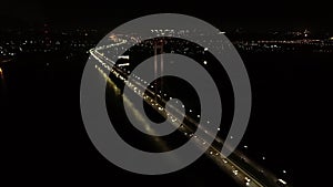 Massive bridge with lots of traffic and bright lights, night city on the background