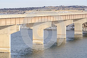 Massive bridge over shiny lake with grassy and snowy landscape background