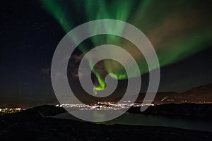 Massive green Aurora Borealis Northern lights shining over the lake and Nuuk city, Greenland