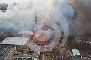 Massive large blaze fire in the city, aerial drone top view brick factory building on fire, hell major fire explosion flame blast