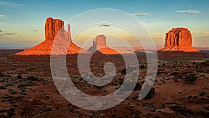 Massive sandstone pillars soar above iconic Monument Valley at sunset photo