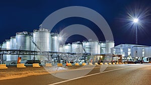 Massive silos at illuminated petrochemical production plant at nighttime, Port of Antwerp, Belgium.