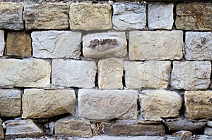 Massive a stone masonry with grey, light brown rectangular rocks. Erased adhesive mixture