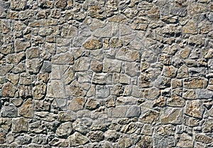 Massive stone wall made of gray and brown rocks with irregular shapes.