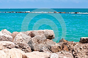 Massive stones rocks lying on the beach as a border between pebble beach Spiaggia del Frate and Adriatic sea waves and flows.
