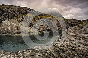 Massive structured steep stone wall with green moss and water