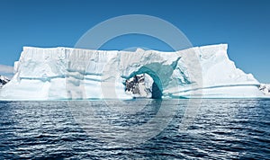 Massive tabular iceberg with arch shape. Booth Island, Antarctica.