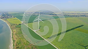 Massive wind turbines on a green field with the city on the background