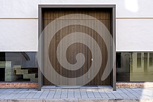 Massive wooden entrance door to modern white house with paving footpath in the city.