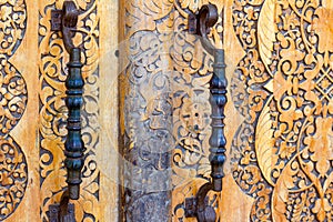 massive wooden front door with wrought iron metal handles in Oriental style