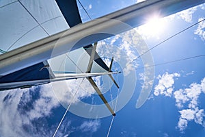Mast and sail of a sailing boat, yacht against cloudy sky on a sunny summer day