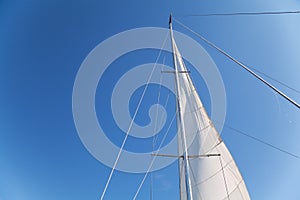 Mast and sail of yacht on blue sky background