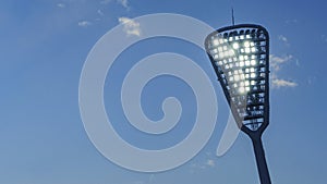 Mast with spotlights illuminate on the stadium. Classic blue sky background. Space for text. Sport concept