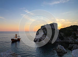 Masted pirate galleon ship sailing the Dubrovnik harbor at sunset