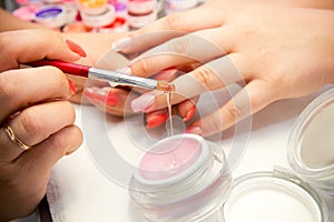 Master applies gel polish on nails in manicure salon