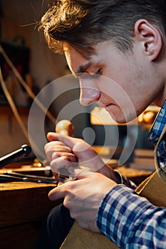 Master artisan luthier working on the creation of a violin. painstaking detailed work on wood.