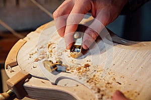 Master artisan luthier working on the creation of a violin. painstaking detailed work on wood.