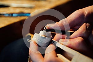 Master artisan luthier working on the creation of a violin. painstaking detailed work on wood.