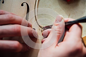 Master artisan luthier working on the creation of a violin. painstaking detailed work on wood. photo