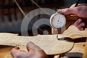 Master artisan luthier working on the creation of a violin. painstaking detailed work on wood.