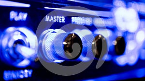 Master audio sound level knob detail on music amplifier blue neon light photo