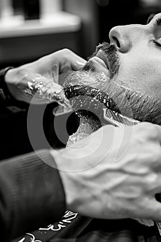 Master barber crafting precise beard line in stylish monochrome shop with spotlighting photo