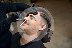 Master barber doing depilation beauty procedure in barbershop