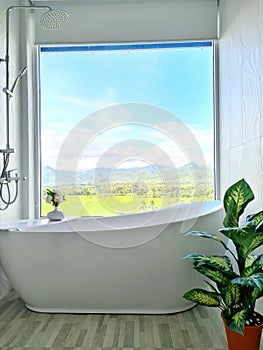 Master Bathroom: Modern Bathtub with View of Sky, Mountain, and Rice field on Sunny Day