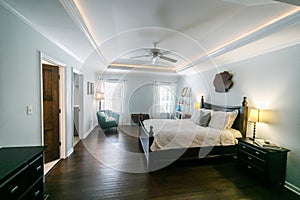 Master bedroom with king size bed and tray ceilings with uplighting and hradwood floors