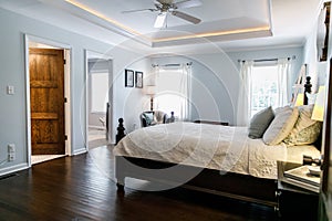 Master bedroom with king size bed and tray ceilings with uplighting and hradwood floors