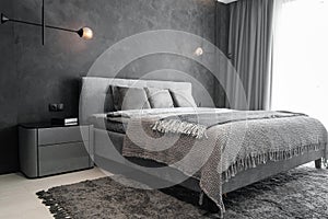 Master bedroom for a lonely stylish man, a bachelor. Modern room with trendy gray interiors, large king-size and lamps.
