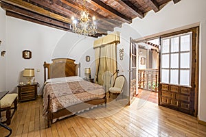 Master bedroom in a vintage stately home with a dark wood coffered ceiling, hardwood slatted floors, and matching antique