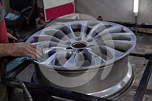 Master body repair man is working on preparing the surface of the aluminum wheel of the car for subsequent painting in the